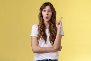 Akılda kalan harika bir fikir. Pusuya düşürülmüş, yaratıcı, iyi görünümlü bayan iş arkadaşı tavsiye veriyor, işaret parmağını kaldırıyor, Eureka jest yapıyor, dudaklarını kıvırıyor, ilginç bir plan yapıyor, sarı arka planda durduğunu düşünüyor.