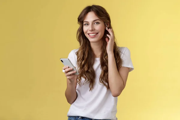 Stylish good-looking carefree urban girl put on earphones listen music wireless earbud touch headphone smiling delighted camera found awesome new track hold smartphone listen music — Stock Photo, Image