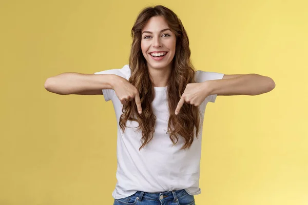 Alegre animada feliz engraçado menina longo belo cabelo apontando para baixo indicador dedos indicam fundo promo rindo alegremente compartilhar emoções positivas recomendar produto publicidade fundo amarelo — Fotografia de Stock