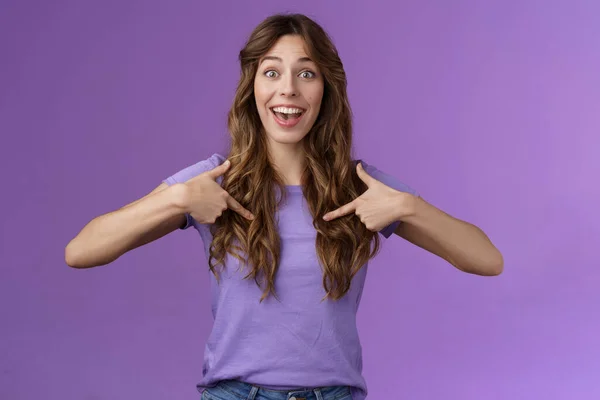 Cheerful lively upbeat entertained happy girl curly hairstyle open mouth amused pointing center herself happily tell own achievement smiling broadly telling friends promotion purple background — Stock Photo, Image