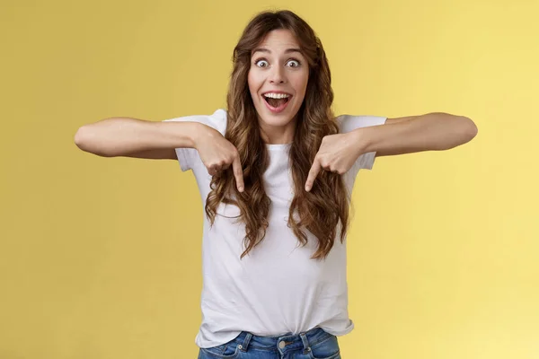 Tentador asombrado impresionado emocionado animado chica fan reaccionar aturdido perder discurso fascinado apuntando hacia abajo emocionado mirada cámara admiración sorpresa completo incredulidad stand amarillo fondo —  Fotos de Stock