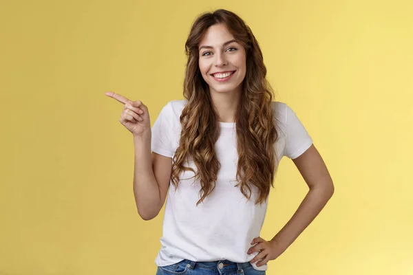 Confiado descarado guapo joven amigable mujer sonriendo satisfecho inclinación cabeza hermosa mirada alegre agarre la mano cintura auto-seguro apuntando a la izquierda dar recomendación amigo dirección ubicación buena promoción — Foto de Stock