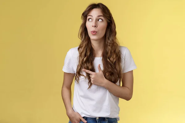 Hmm interesting wow. Curious silly cute pretty woman long curly hairstyle folding lips admiration tempting try out new menu look pointing upper left corner fascinated intrigued yellow background — Stock Photo, Image