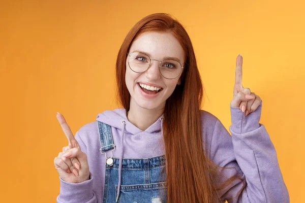 Lively enthusiastic millennial redhead girl coworker having fun celebrating small break joyfully dancing pointing up index fingers singing smiling white teeth promoting product, orange background — Stock Photo, Image