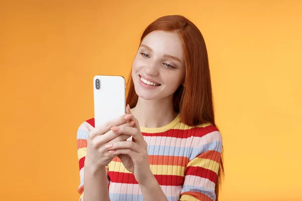 Linda chica femenina tierna pelirroja glamour joven sosteniendo teléfono inteligente tomando fotos verano vibraciones urbanas blogger femenina tiro post historia en línea de pie felizmente fondo naranja sonriendo —  Fotos de Stock