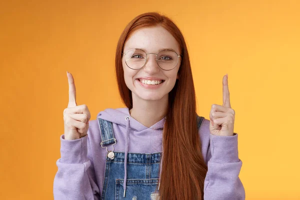 Lively charismatic pleasant redhead female student helpful pointing up index fingers showing awesome promo offer smiling delighted white teeth indicating advertisement recommend use product — Stock Photo, Image