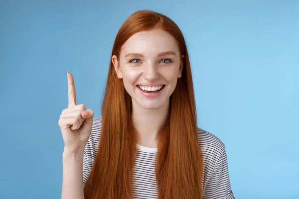 Tengo una idea excelente para ti. Atractivo feliz amigable de aspecto útil pelirroja asistente de la tienda mostrando precioso vestido cliente señalando el dedo índice sonriente feliz ayuda, fondo azul — Foto de Stock