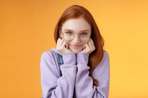 Υπέροχο χαριτωμένο κοκκινομάλλα γλυκό ανόητο κορίτσι geek φοιτητής φορώντας γυαλιά άπαχο χέρι χαμογελώντας τρυφερά ματιά αγάπη λατρεύουν ακούσετε αισθησιακές εξομολογήσεις φίλο, στέκεται πορτοκαλί φόντο — Φωτογραφία Αρχείου