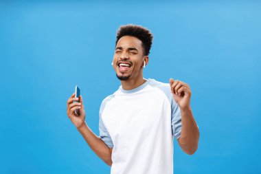 Keyifli ve tasasız yakışıklı Afro-Amerikan erkeğinin portresi. Günlük tişörtleriyle dans ediyor. En sevdiği şarkı boyunca telsiz kulaklıkla müzik dinliyor.