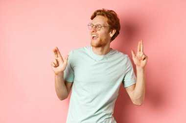 Neşeli kızıl saçlı, müzik dinleyen, dans eden, zafer kazanan ya da başarıyı kutlayan pembe arka planda duran adam.