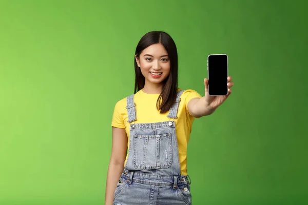 Självsäker attraktiv asiatisk brunett show smartphone skärm, införa nya telefon appllication, slå poäng mobiltelefon spel, ler glad, ge rekommendation följa egen blogg — Stockfoto