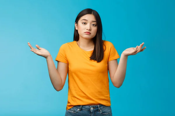 Shit happens. Indifferent absolutely careless female student not care how accident happened shrugging, look camera questioned unaware, hard answer, clueless how deal situation, stand blue background — Stock Photo, Image