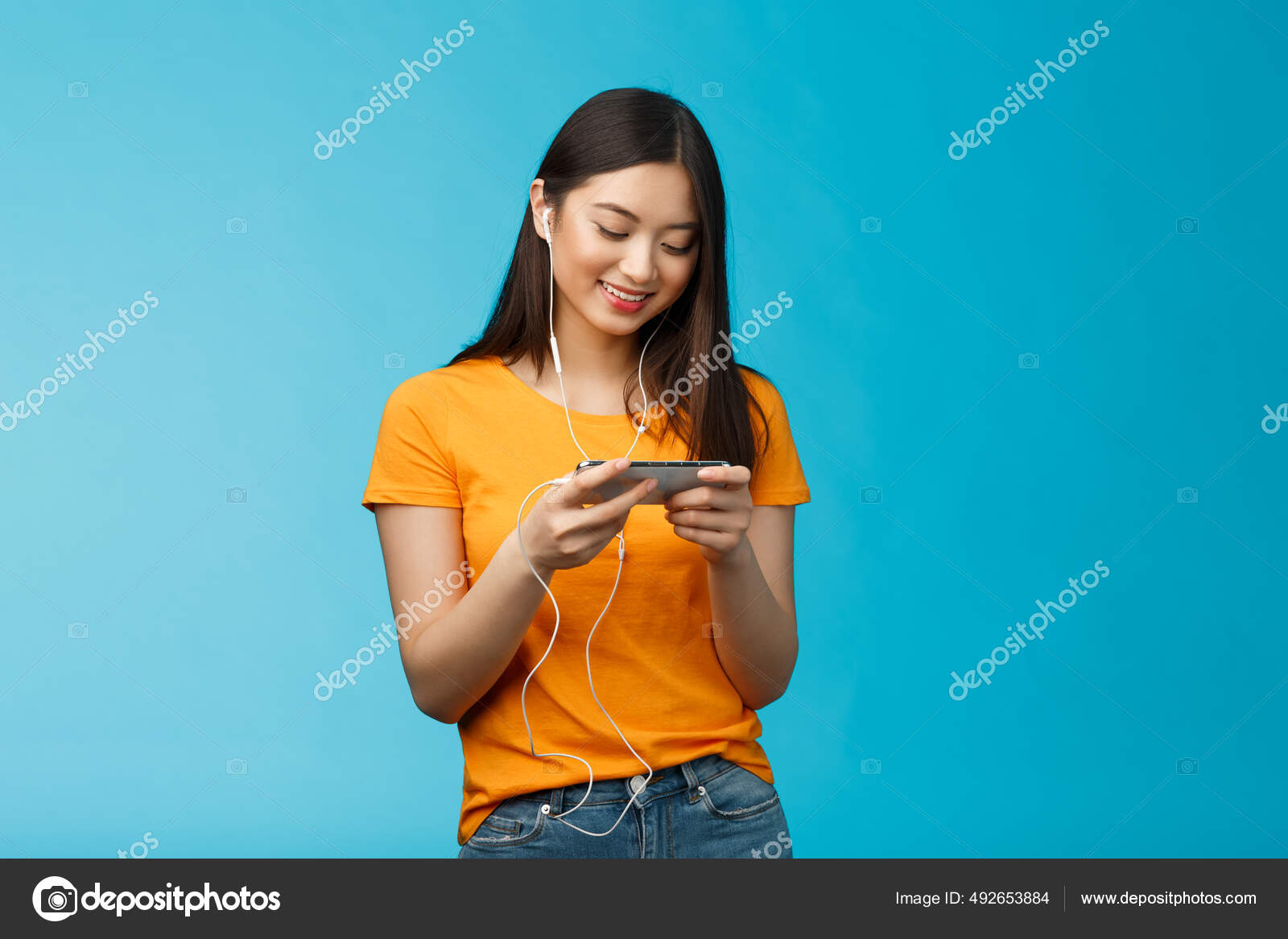 Mulher urbana nova que usa o telefone app e fones de ouvido sem fio para  ouvir música ou jogar jogos de vídeo online.