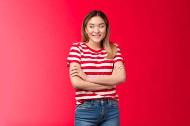 Aptal, sevimli, güzel Asyalı sarışın kız utangaç, cilveli sırıtan, çapraz kollu, göğüslü, rahat poz veren, kız arkadaş sevgilisiyle buluşan, güzel, kırmızı arka planda duran, kaygısız kız.