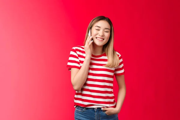 Ξανθιά Ασιάτισσα που κάνει αστεία συζήτηση, μιλάει στο τηλέφωνο, κλείνει τα μάτια χαμογελώντας χαρούμενα καλώντας τον φίλο της να κρατήσει το smartphone κοντά στο αυτί, γελώντας με ένα ξεκαρδιστικό φωνητικό μήνυμα — Φωτογραφία Αρχείου