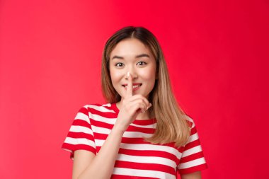 Şirin, arkadaş canlısı Asyalı kız arkadaş gizli dedikoduları paylaşıyor, gülümsüyor gizli fok dudaklarına söyleme, işaret parmağını ağzında tut şşşş, de ki: