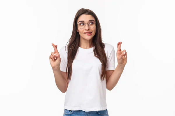 Waist-up portrait of hopeful pretty brunette female anticipating miracle, biting lip tempting, want dream come true, look away thoughtful, cross fingers good luck, making wish, white background — Stock Photo, Image