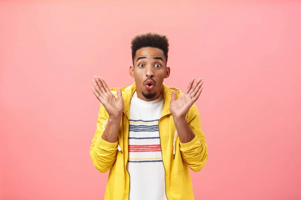 Man erfährt schreckliche Neuigkeiten, die auf Freunde warten. Aufgeregt entzückt Afroamerikaner mit Bart in trendiger gelber Jacke über T-Shirt, die Palmen in überraschter Pose hebt und die Lippen zusammenfaltet begeistert — Stockfoto