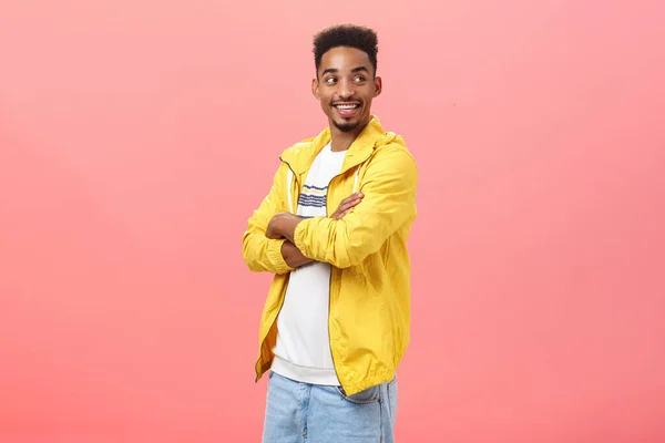 Stylish confident handsome african american mature guy with beard and afro hairstyle standing half-turned and turning right with enthusiastic amazed expression holding hands crossed over pink wall — Stock Photo, Image