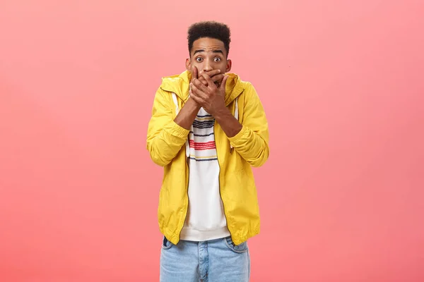 Waist-up shot of shocked stunned good-looking dark-skinned young male student in stylish outfit covering mouth with palms being in shook and stupor, posing over pink background — Stock Photo, Image
