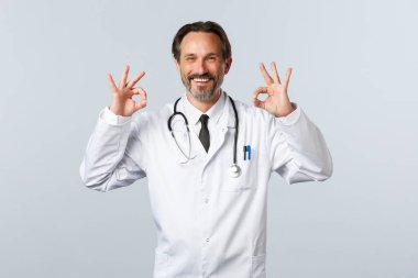 Covid-19, koronavirüs salgını, sağlık çalışanları ve pandemik konsept. Tatmin olmuş mutlu doktor kalitesini garanti ediyor. Terapist iyi niyet göstergesi ve gülümseme. Memnun oldum. Reklam verin.