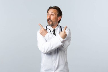 Covid-19, koronavirüs salgını, sağlık çalışanları ve pandemik konsept. Beyaz önlüklü kararsız doktor, parmaklarını yana doğru gösteriyor ve değişkenlere bakıyor, seçim yapıyor.