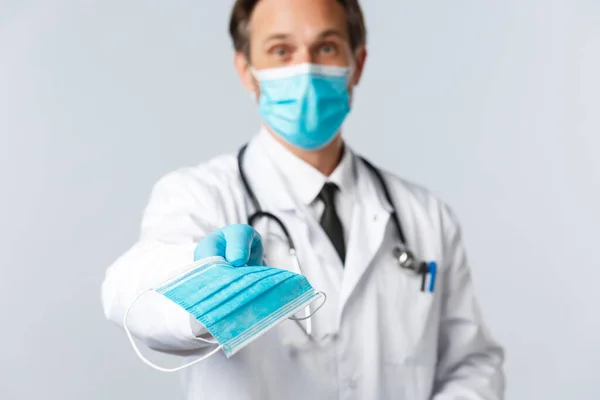Covid-19: 바이러스 예방, 의료 종사자 및 예방 개념. 우호적 인 의사는 코로나 바이러스가 유행하는 동안 환자의 건강을 유지하기 위해 환자에게 의료용 마스크를 줍니다. PPE 를 투여하는 의사 — 스톡 사진