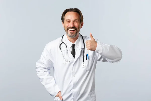 Covid-19, coronavirus outbreak, healthcare workers and pandemic concept. Optimistic happy doctor advice medication or clinic service, ensure quality, showing thumbs-up in approval — Stock Photo, Image