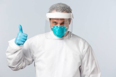 Covid-19, virüs, sağlık çalışanları ve aşı konsepti. Koruyucu ekipman ve medikal solunum cihazlarında kararlı ve kendine güvenen bir doktor hasta üzerinde çalışmaya hazır olduğunu gösteriyor.