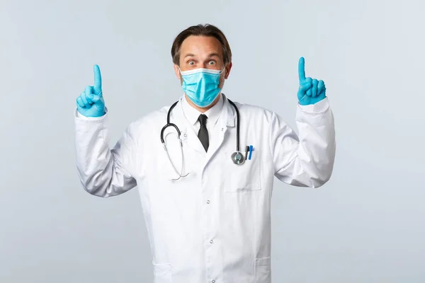 Covid-19: 바이러스 예방, 의료 종사자 및 예방 개념. 의료 마스크와 장갑을 끼고 좋은 소식을 보여 주기 위해 손가락을 들고 놀란 남성 의사 — 스톡 사진