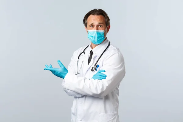 Covid-19: 바이러스 예방, 의료 종사자 및 예방 개념. 왼쪽을 실망시키는 의료용 마스크와 장갑을 끼고 있는 의심 스러운 의사는 좌절 과 의견의 불일치를 표현 한다 — 스톡 사진