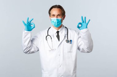 Covid-19, virüsü önleme, sağlık çalışanları ve aşı konsepti. Doktor güvenlik garantisi ya da klinik hizmetlerinin kalitesi, onaylı jest gösterme, tıbbi maske ve eldiven giyme