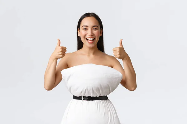 아름다움, 패션, 그리고 소셜 미디어 개념. 즐거운 미소짓는 이시아 여성이 인터넷 베개 도전에 재미있게 참여하고 있고, 폐기물 주위에 드리워진 베개와 벨트로 드레스를 만들고, 엄지손가락을 치켜올리고 있다. — 스톡 사진