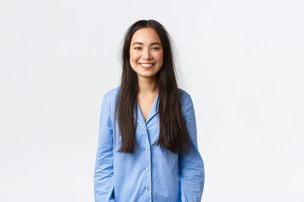 Souriant belle fille asiatique en pyjama bleu regardant ravi, avoir les cheveux sales après le réveil et se lever du lit, debout fond blanc a eu une bonne nuit de sommeil, exprimer sa satisfaction — Photo