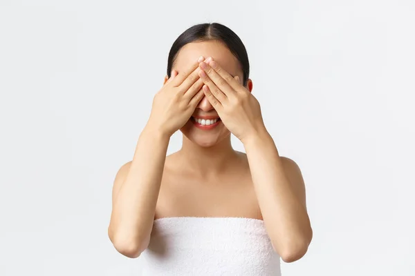 Kecantikan, kosmetologi dan konsep salon spa. Close-up of silly happy, pretty asian girl in bath towns smile upbeat as waiting with antiation to open eyes, close eyes with hands, white background — Stok Foto