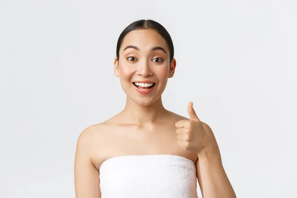 美容美发和温泉沙龙的概念。满意的亚洲女性客户穿着白色毛巾，露出大拇指，笑容满面，推荐美容院，保证质量 — 图库照片