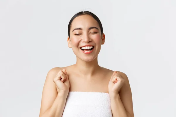 Kecantikan, kosmetologi dan konsep salon spa. Close-up dari wanita asia cantik yang bahagia dengan handuk mandi menutup mata riang dan tertawa dari sukacita, iklan klinik kecantikan, terapi pijat, penyimpangan — Stok Foto