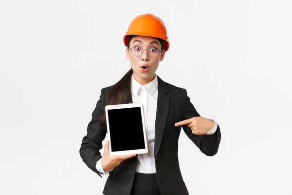 Imponujący i zaskoczony azjatycki inżynier, technik w obszarze przemysłowym nosić kask bezpieczeństwa i garnitur biznesowy, wskazując palcem na wykresie zysków, diagram na ekranie tabletu cyfrowego, wyglądają zdumiewające — Zdjęcie stockowe