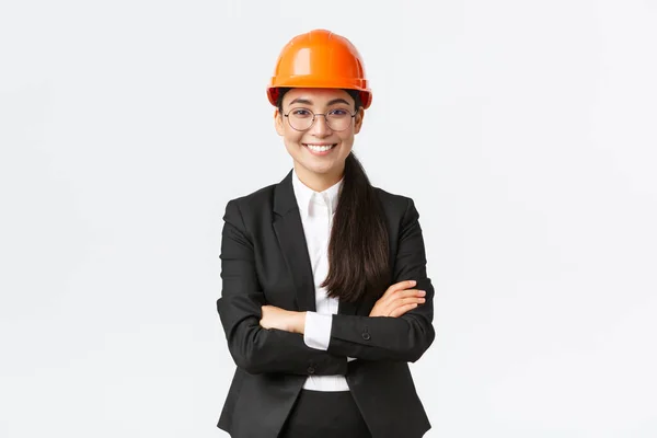 Profissional sorrindo asiático empresária em capacete de segurança e terno cruz braços e olhando confiante, vendendo novos edifícios. Gerente de construção, engenheiro mostrando ao redor, cumprimentando investidores — Fotografia de Stock