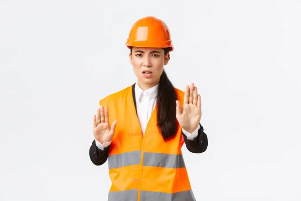 Teleurgesteld boze Aziatische vrouwelijke ingenieur in veiligheidshelm en reflecterende kleding te zeggen stop, verbieden en oneens met de bouw manager, tonen genoeg, geen gebaar, witte achtergrond — Stockfoto