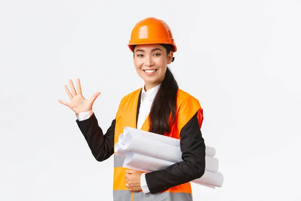 Glimlachende professionele Aziatische vrouwelijke ingenieur, architect geven vijf maanden voor de bouw, dragen blauwdruk van het project en kijken naar de camera, garanderen afwerking werk in de tijd, witte achtergrond — Stockfoto