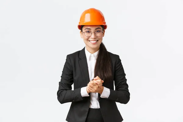 Lachende professionele Aziatische zakenvrouw in veiligheidshelm en business suit introduceren onderneming aan klanten of investeerders, rondleiden, het maken van presentatie op de bouwplaats — Stockfoto