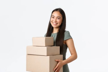 Küçük işletme sahipleri, ev kavramından başlayarak ve çalışarak. Gülümseyen genç mağaza müdürü, Asyalı iş kadını paketleri toplar, siparişleri kutulara koyar ve teslimat şirketine taşır.