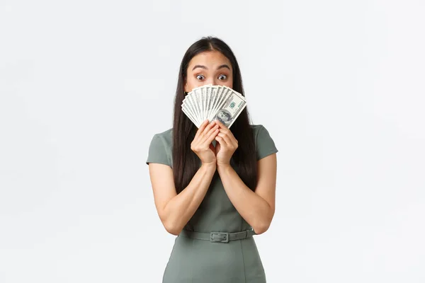 Emocionado joven mujer asiática feliz corriendo startup y recibir el primer cheque de pago, sosteniendo el dinero cerca de la cara y mirando sorprendido, haciendo cara alegre de gran suma de dinero en efectivo, de pie fondo blanco — Foto de Stock
