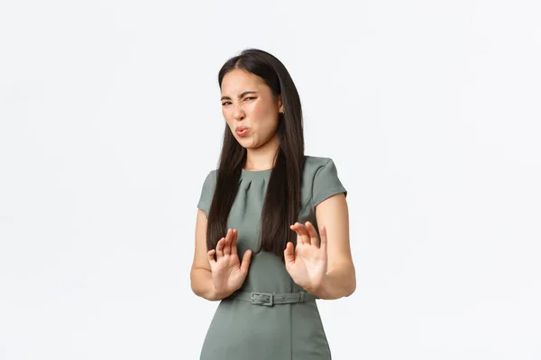 Small business owners, women entrepreneurs concept. Disgusted asian woman in dress, grimacing from aversion, feeling sick, showing refusal, stop gesture, rejecting offer, white background — Stock Photo, Image