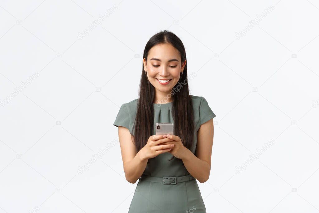 Small business owners, women entrepreneurs concept. Smiling young female running startup in internet, checking messages from clients, texting someone on mobile phone, using smartphone