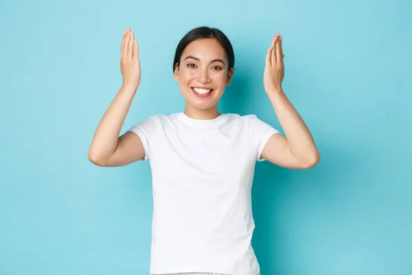 快乐快乐的亚洲女孩睁开眼睛，笑容满面，满面春风，举手表决蓝色背景，庆祝生日，为礼物感到惊奇 — 图库照片