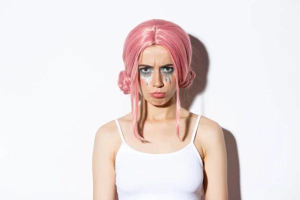 Närbild av arg söt flicka med rosa peruk och glamour makeup, sura arg på någon, känsla förolämpad, står över vit bakgrund — Stockfoto