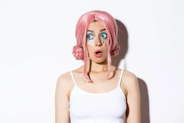 Närbild av imponerad attraktiv flicka i rosa peruk, öppen mun i vördnad och tittar vänster, står över vit bakgrund — Stockfoto
