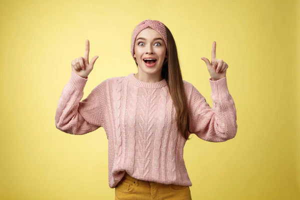 Extático divertido positivo jovem de 20 anos mulher vestindo camisola casual, cabeça cair mandíbula espantado olhando espantado, surpreso apontando para cima animado, otimista de ver incrível promo sobre a parede amarela — Fotografia de Stock